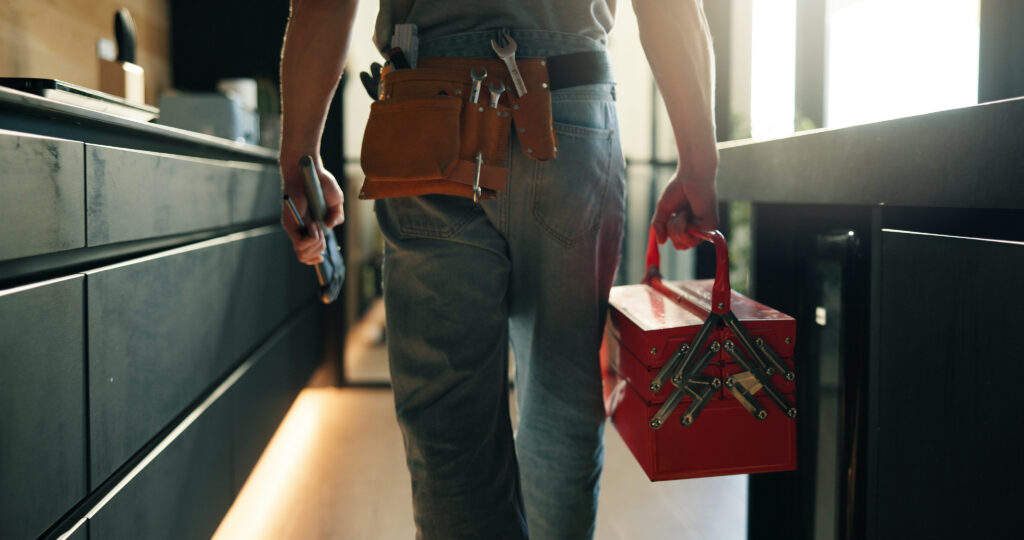Walking, tool box and back of man in home for maintenance, service or repair job in kitchen. Equipment, customer care and male contractor with plumbing career at client house for leak inspection
